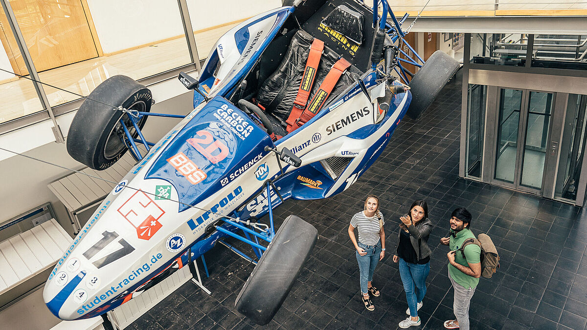 Studierende schauen sie einen der ersten Racing Autos in der Fakultät für Maschinenbau an.